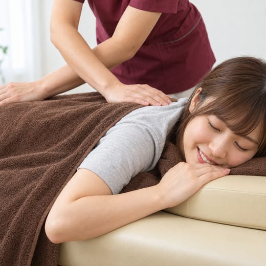 うつぶせで背中のマッサージを受ける女性（イメージ写真）